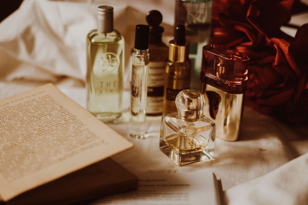 A collection of premium men's fragrance bottles displayed on a dark wooden dresser with soft lighting, illustrating the differences between Eau de Toilette, Eau de Parfum and Parfum.