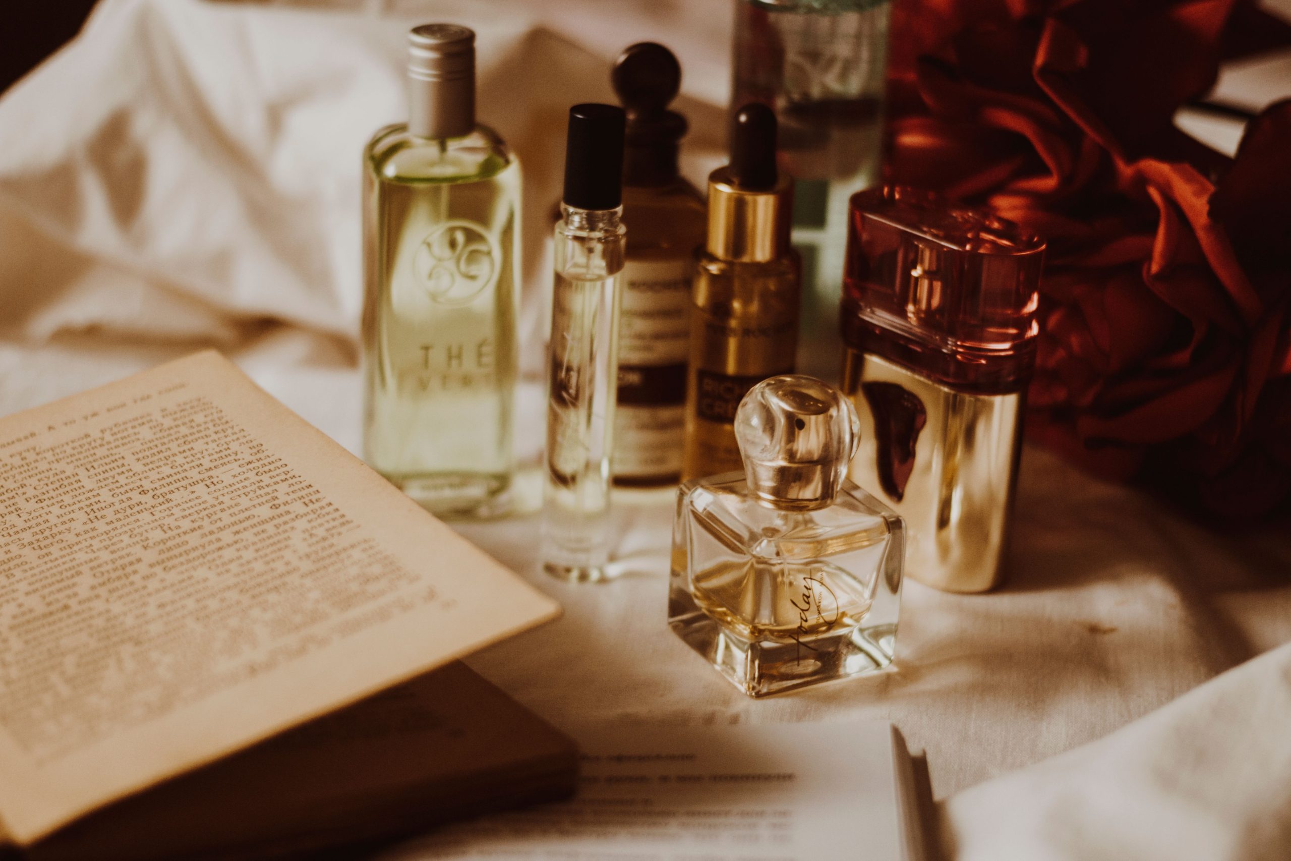 A collection of premium men's fragrance bottles displayed on a dark wooden dresser with soft lighting, illustrating the differences between Eau de Toilette, Eau de Parfum and Parfum.