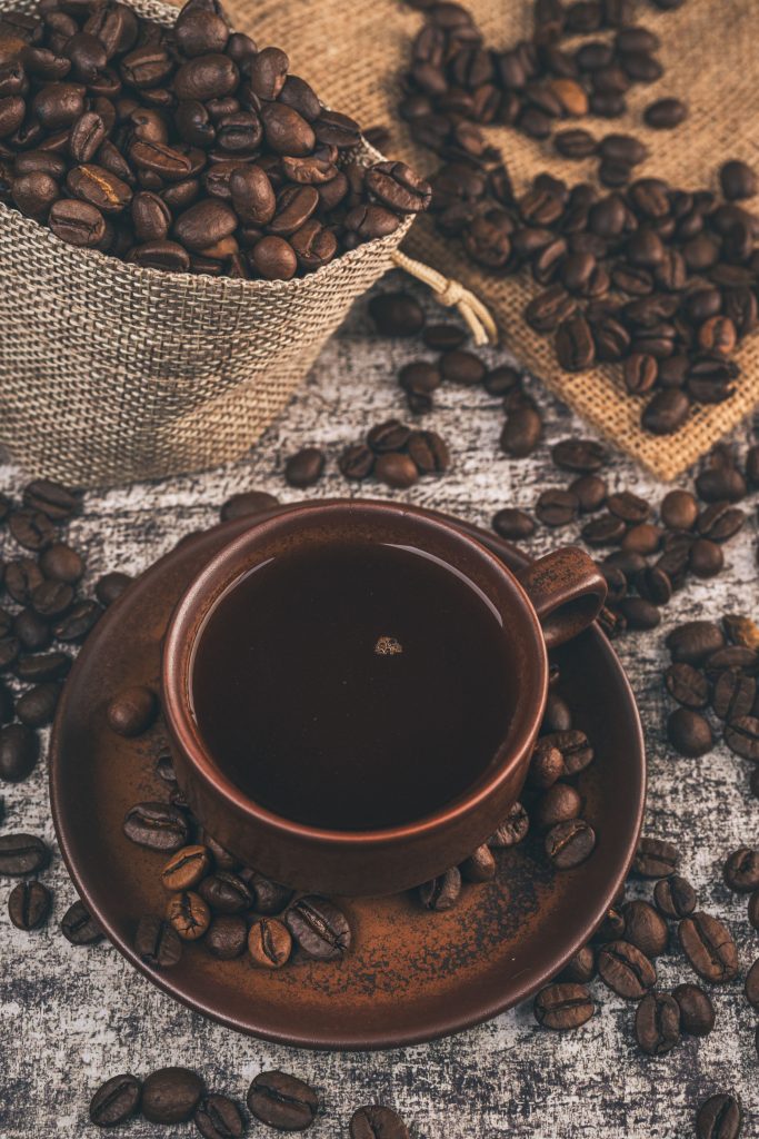 A beautifully styled cup of freshly brewed coffee beside whole Arabica and Robusta beans on a dark wooden table, highlighting the contrast between the world's two most popular coffee varieties.